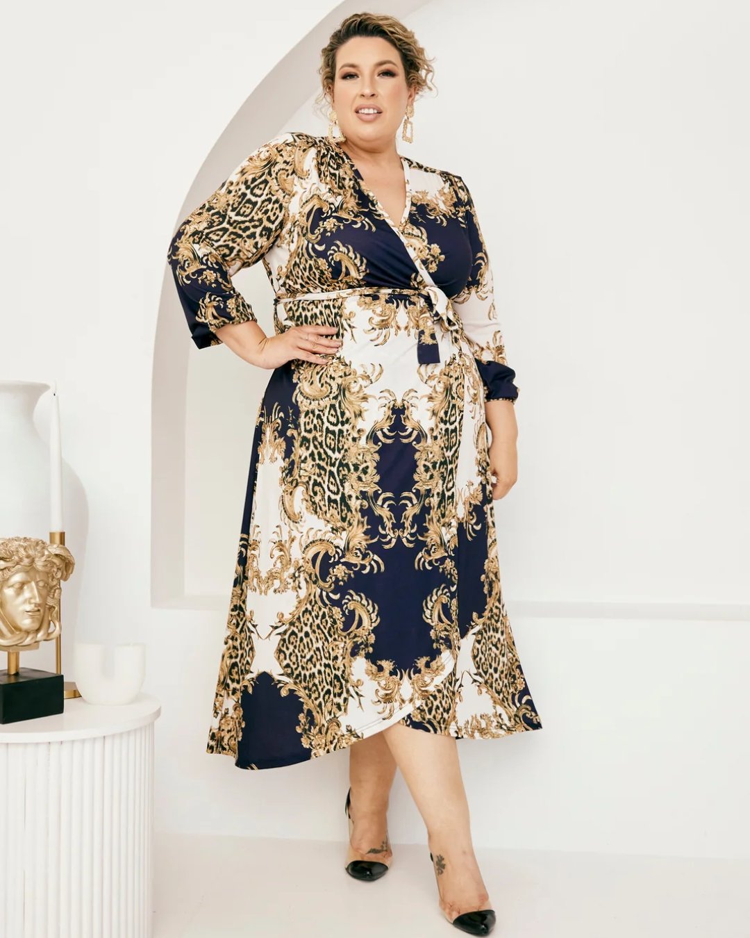 Plus size woman poses in a baroque print wrap dress