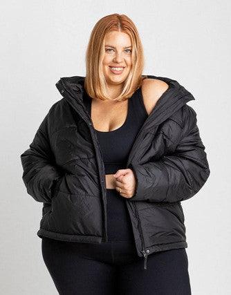 Plus size woman poses in a black crop top and matching puffer jacket