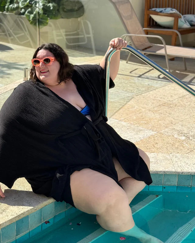 plus size woman beside the pool covered by black robe