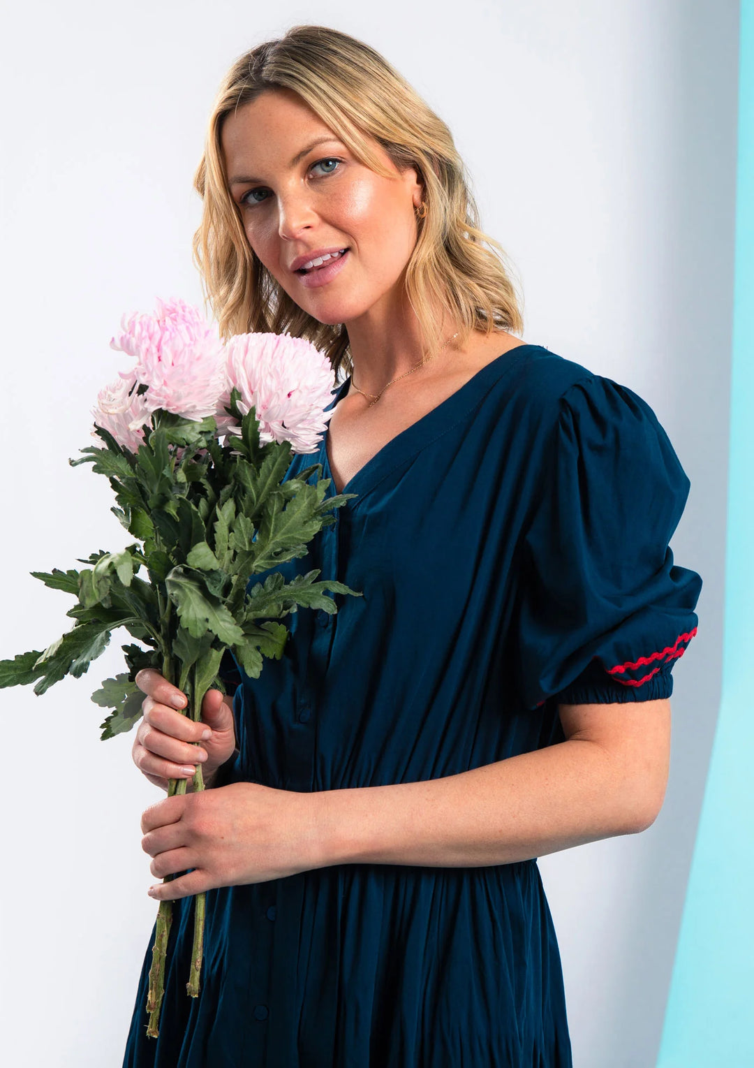 woman wearing navy dress with puff sleeves holding flowers