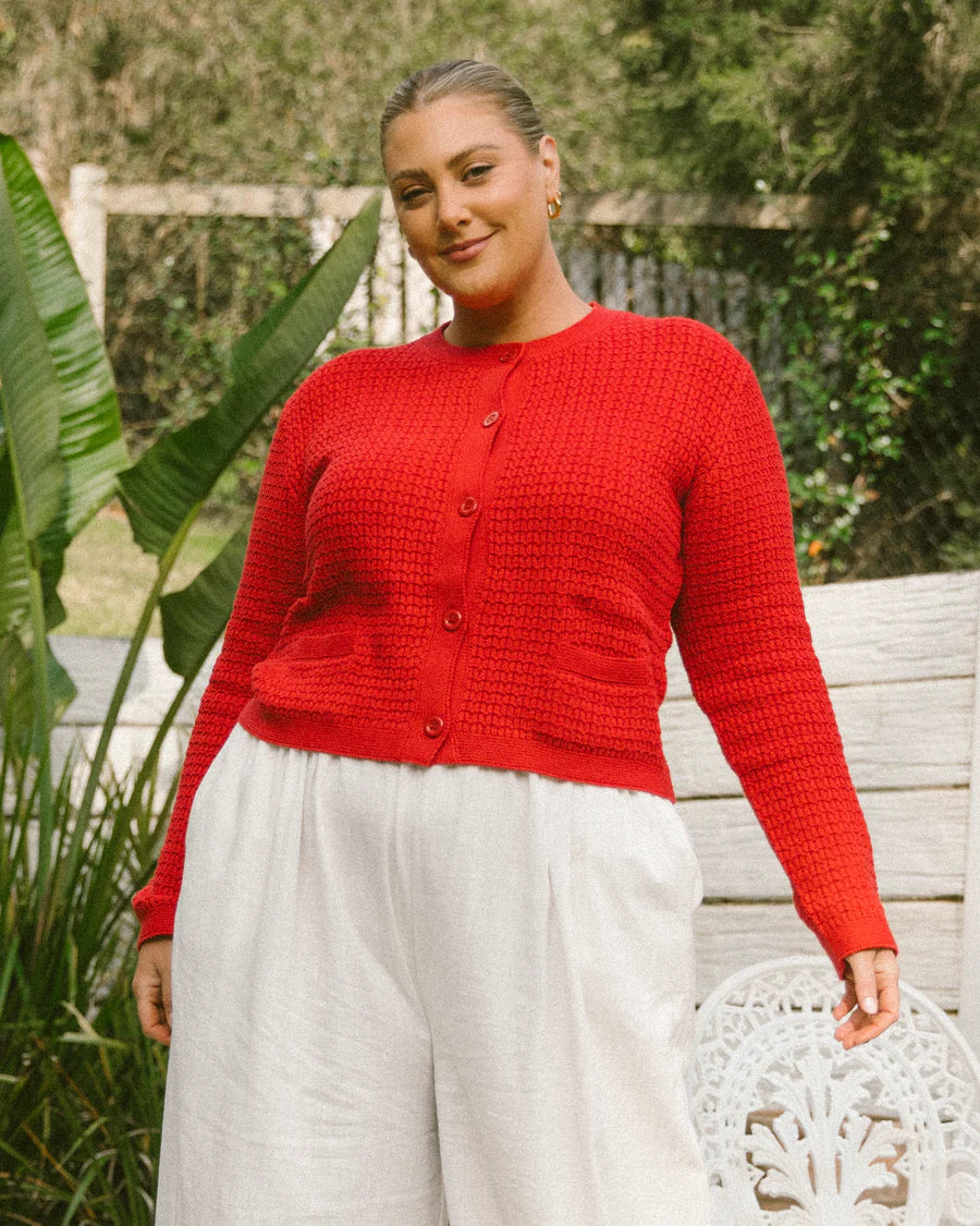 plus size woman wearing red cardigan and cream pants