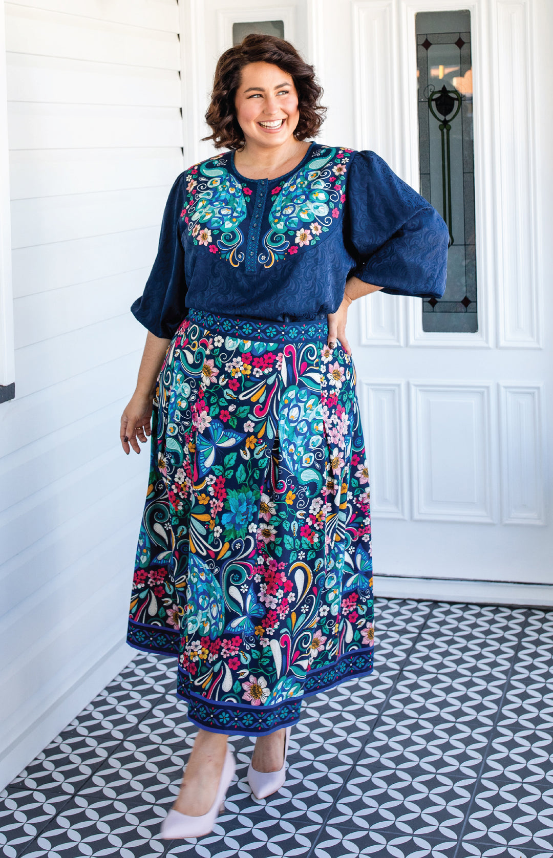 plus size woman wearing navy flowy sleeve top and flower printed maxi skirt