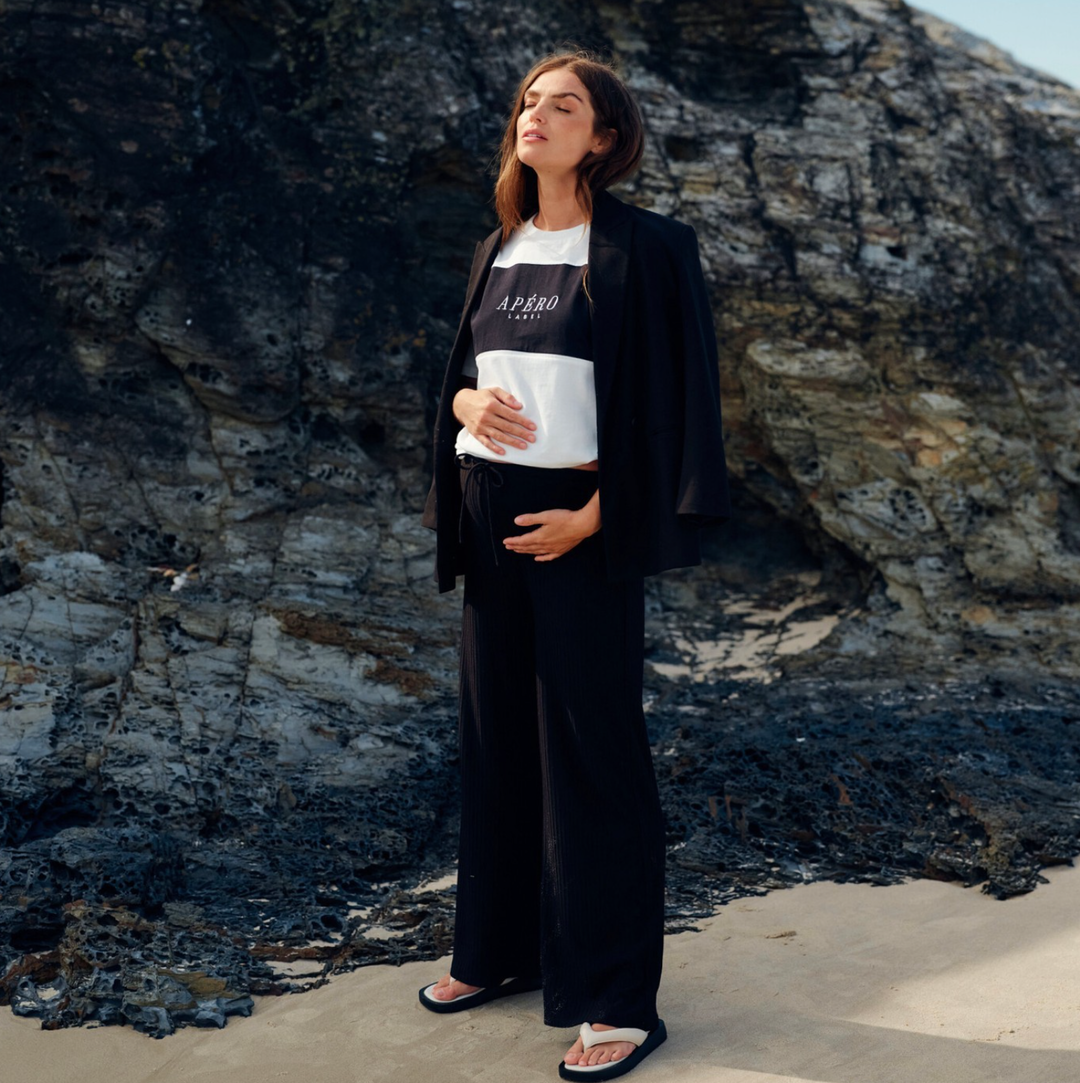 pregnant woman in shirt, black pants and coat