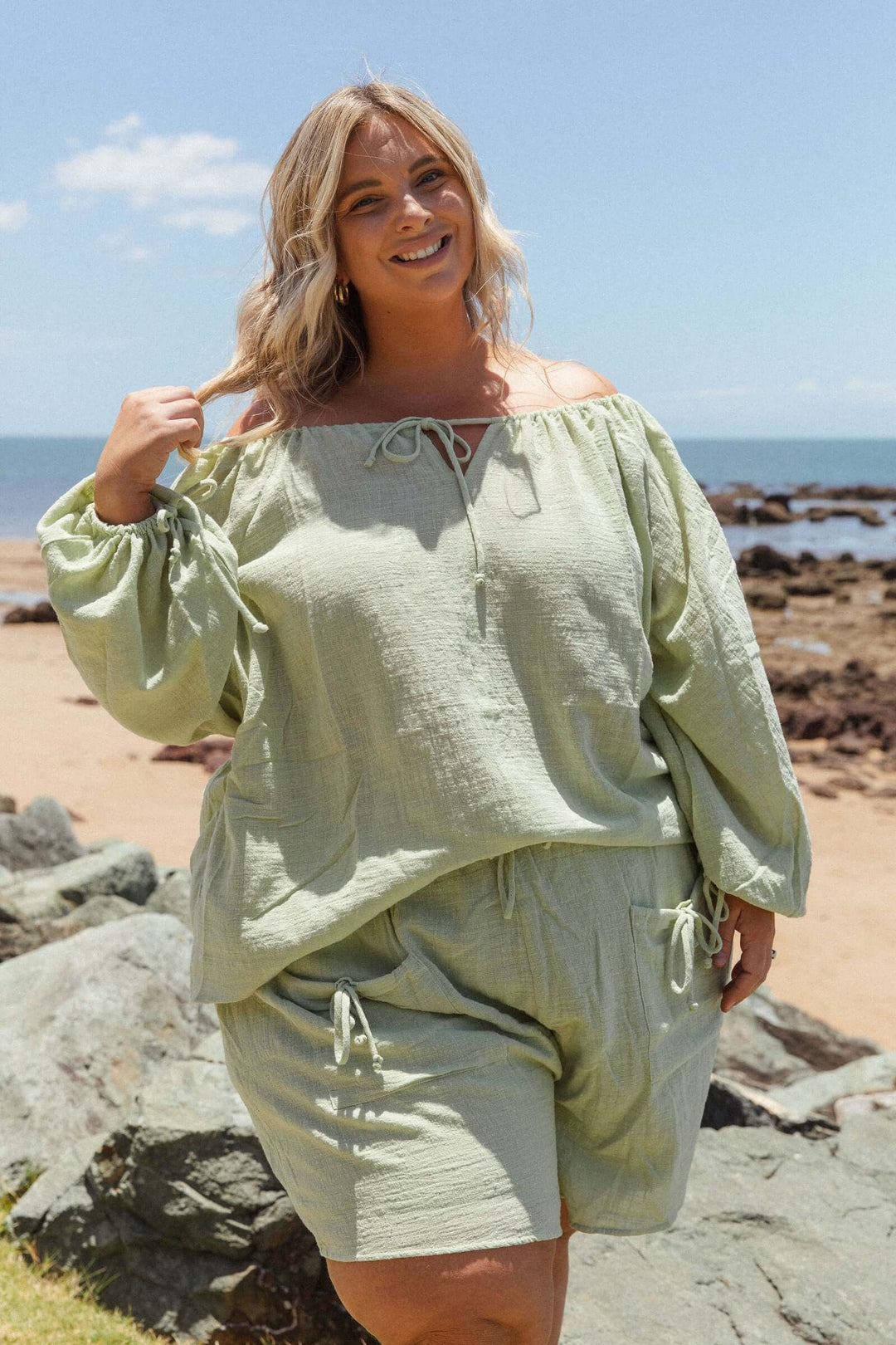 plus size woman wearing pistachio coloured long sleeve top and shorts